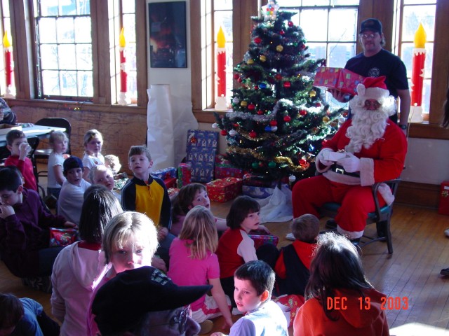 December 2003 - Santa's helper, Captain Mike Jerome, assisting in handing out gifts during the kid's Chrismas party